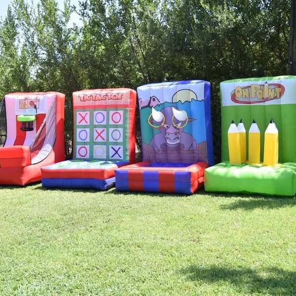 Four colorful inflatable carnival games lined up on a lawn